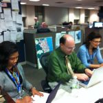 Journalists working at computers in a newspaper newsroom.