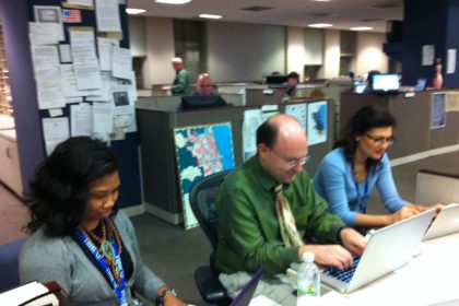 Journalists working at computers in a newspaper newsroom.