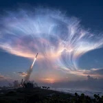 SpaceX rocket launch creating a glowing jellyfish cloud in the twilight sky